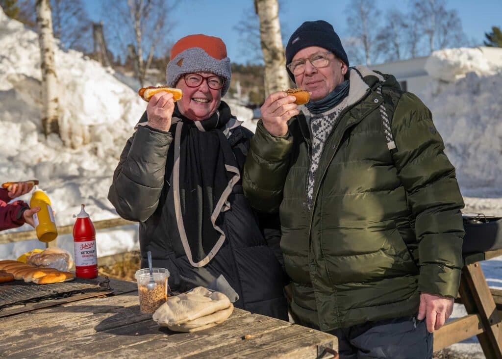 Glada campinggäster grillar korv tillsammans i snön vid First Camp Lugnet - Falun